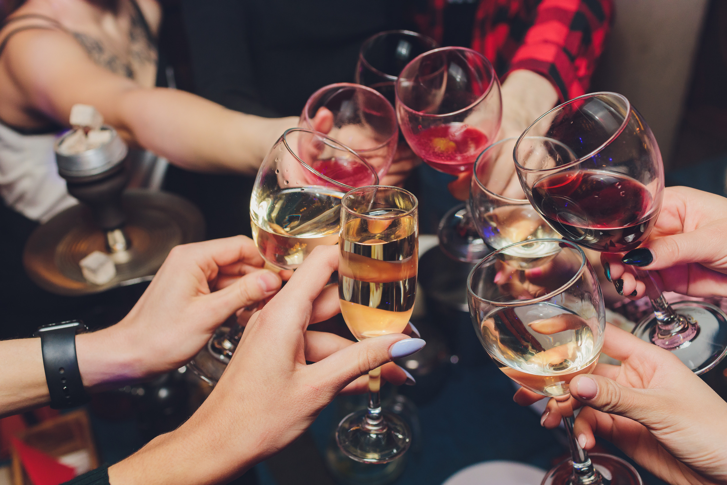 People's hands holding wine glasses that they are clinking